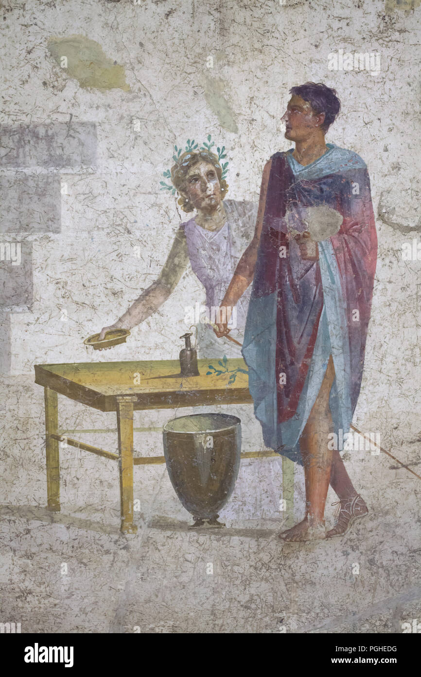 Jason depicted in the Roman fresco from the House of Jason (Casa di Giasone) in Pompeii (20-25 AD), now on display in the National Archaeological Museum (Museo Archeologico Nazionale di Napoli) in Naples, Campania, Italy. Jason recognisable by his missing sandal depicted next to the servant places the items required in the sacrificial ritual on a trapeza (Roman low table). Stock Photo