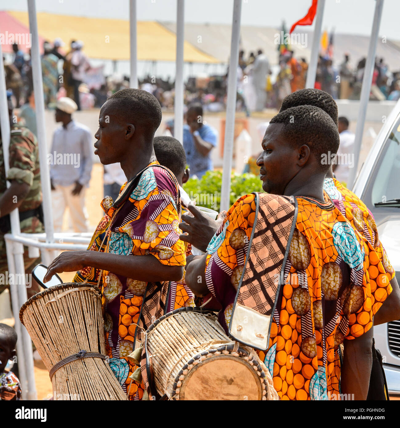 OUIDAH, BENIN - Jan 10, 2017: Unidentified Beninese men in colored suits carry drums at the voodoo festival, which is anually celebrated on January, 1 Stock Photo