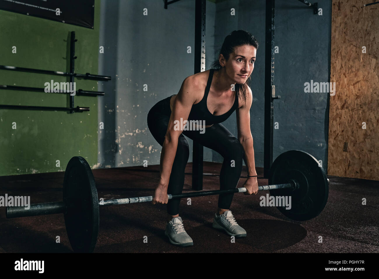 Muscular young fitness woman lifting a weight crossfit in the gym, fitness woman deadlift barbell. Stock Photo