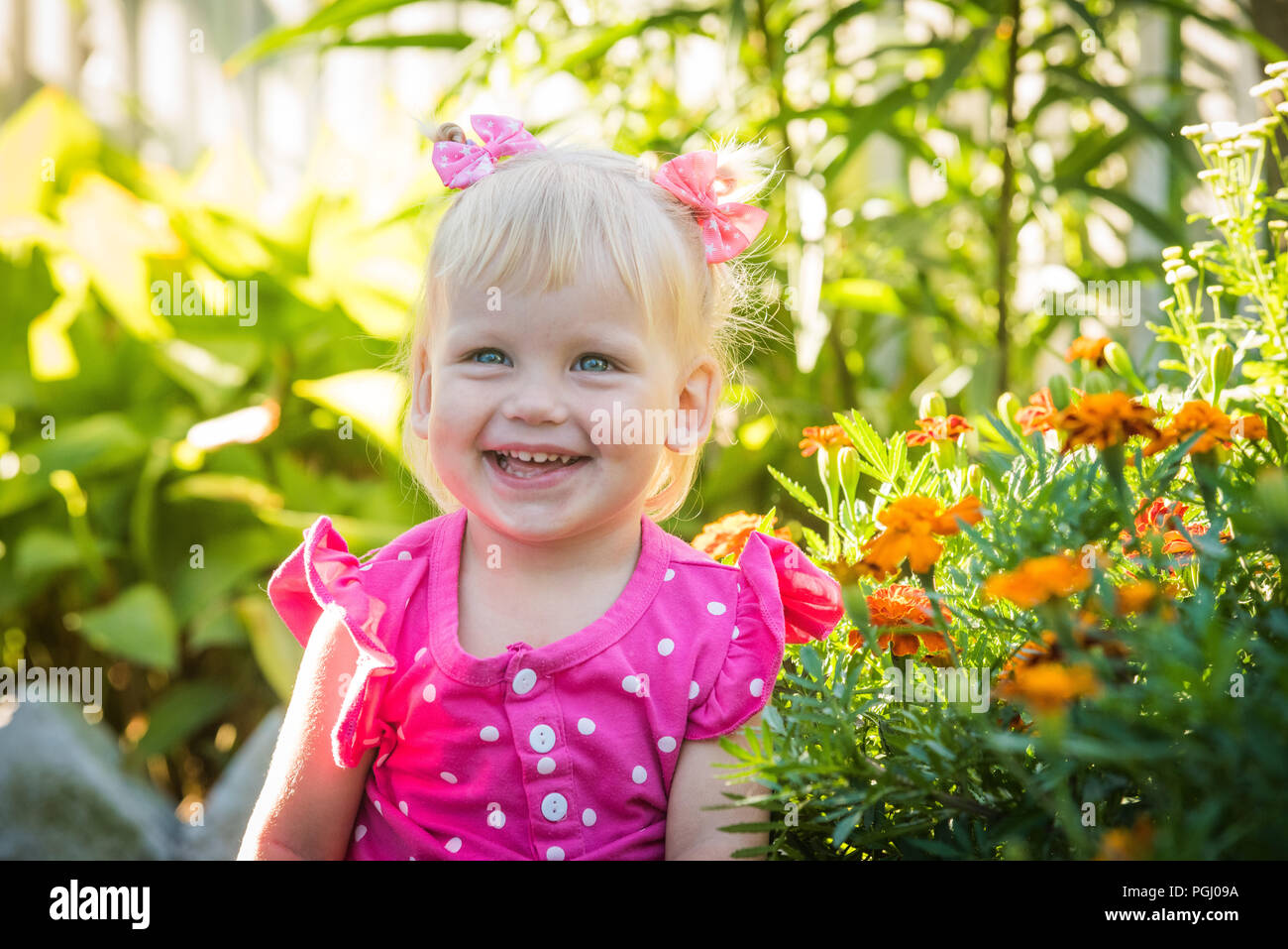 Beautiful happy little baby girl on a green bright summer background Stock Photo