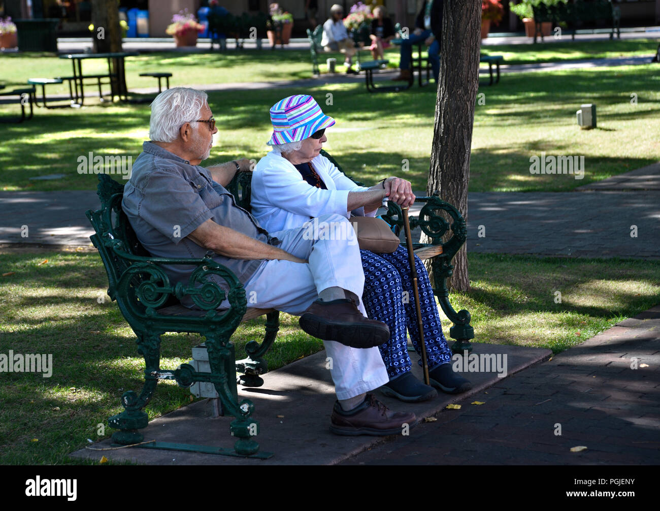 A senior couple sit on a park bench in Santa Fe, New Mexico. Stock Photo