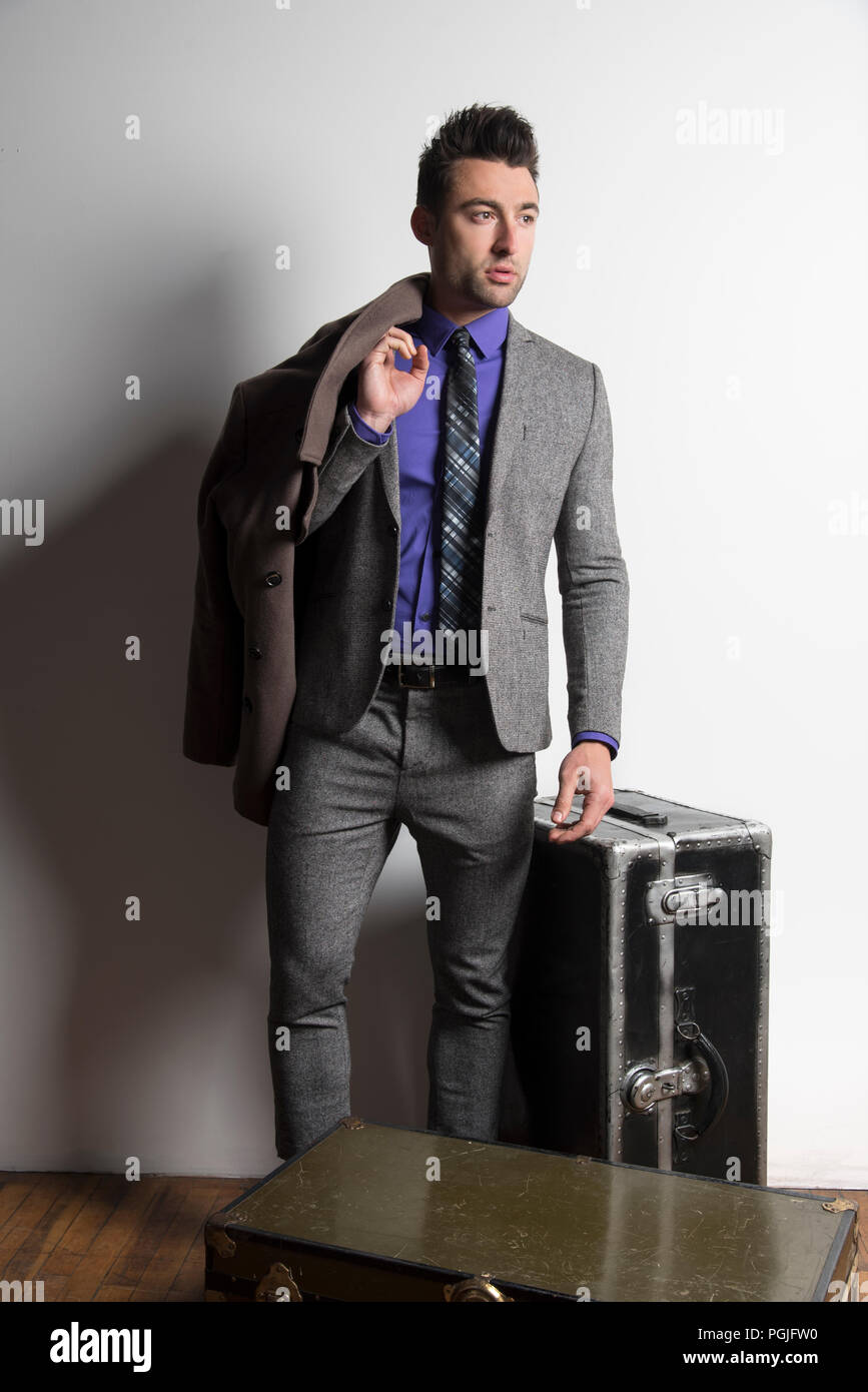 A handsome well dressed man standing beside steamer trunks.   Exclusive image. Stock Photo