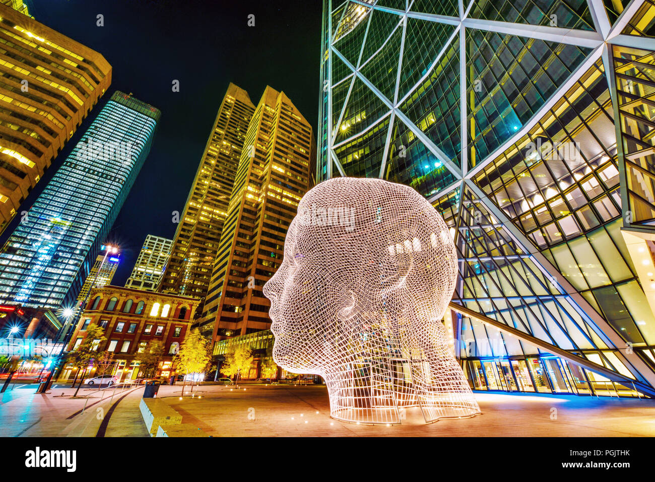 Night view of the popular 'Wonderland' sculpture by famous artist Jaume Plensa sits in-front of The Bow tower in Calgary, Alberta,Canada Stock Photo