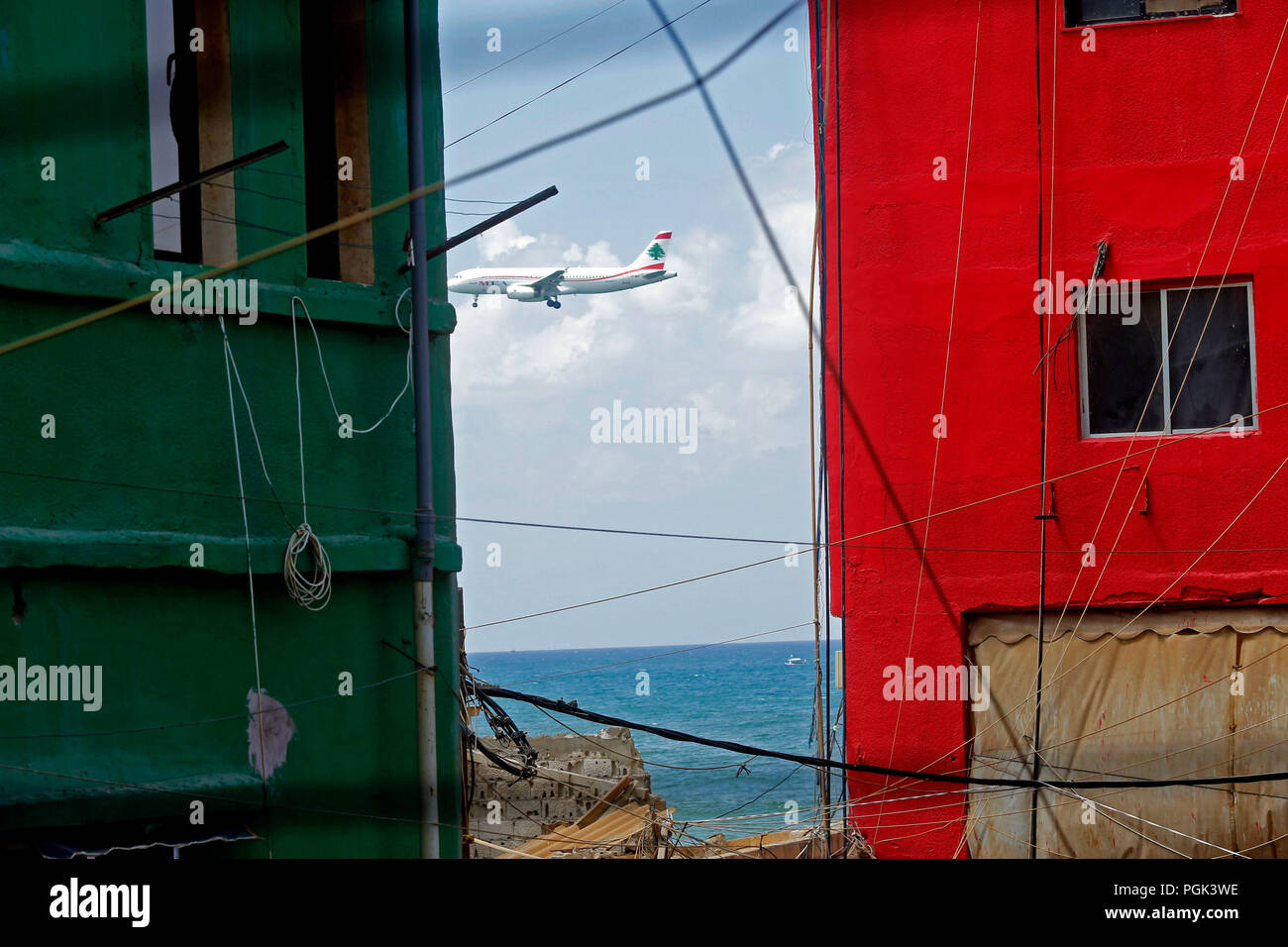 Ouzai, Lebanon. 26th Aug, 2018. A plane flies by buildings with colorful paintings in Ouzai, south of Beirut, Lebanon, on Aug. 26, 2018. Credit: Bilal Jawich/Xinhua/Alamy Live News Stock Photo