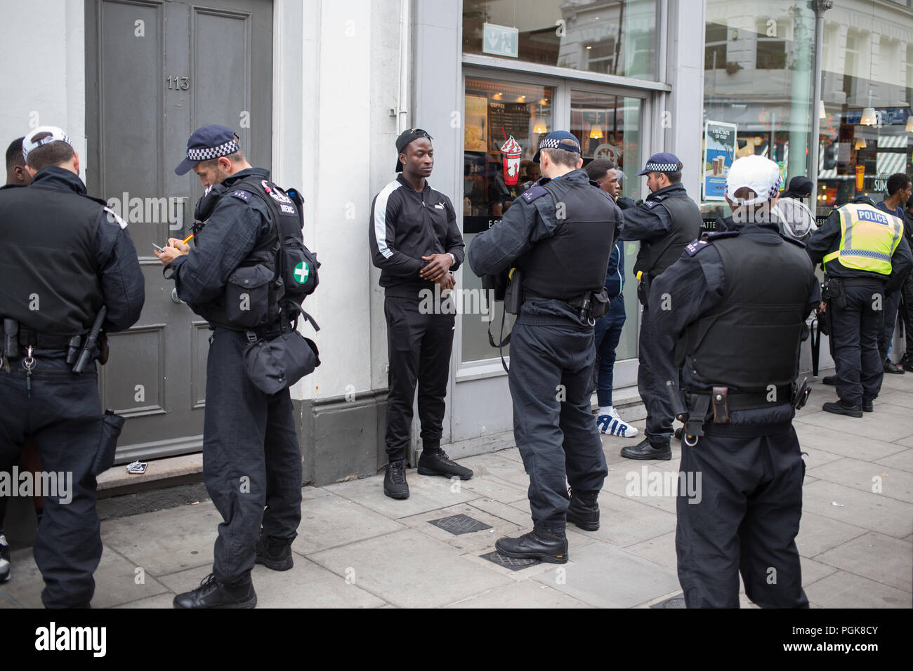 London UK 27th August 2018 Police were pictured carrying out stop-and-search at the Notting Hill Carnival after being handed extra powers in a bid they say to curb violent crime. Police stop and search young black men at the annual Notting Hill Carnival. For many victims of this experience it is a source of anger and frustration as they feel targetted due to their skin colour.  Credit: Thabo Jaiyesimi/Alamy Live News Stock Photo