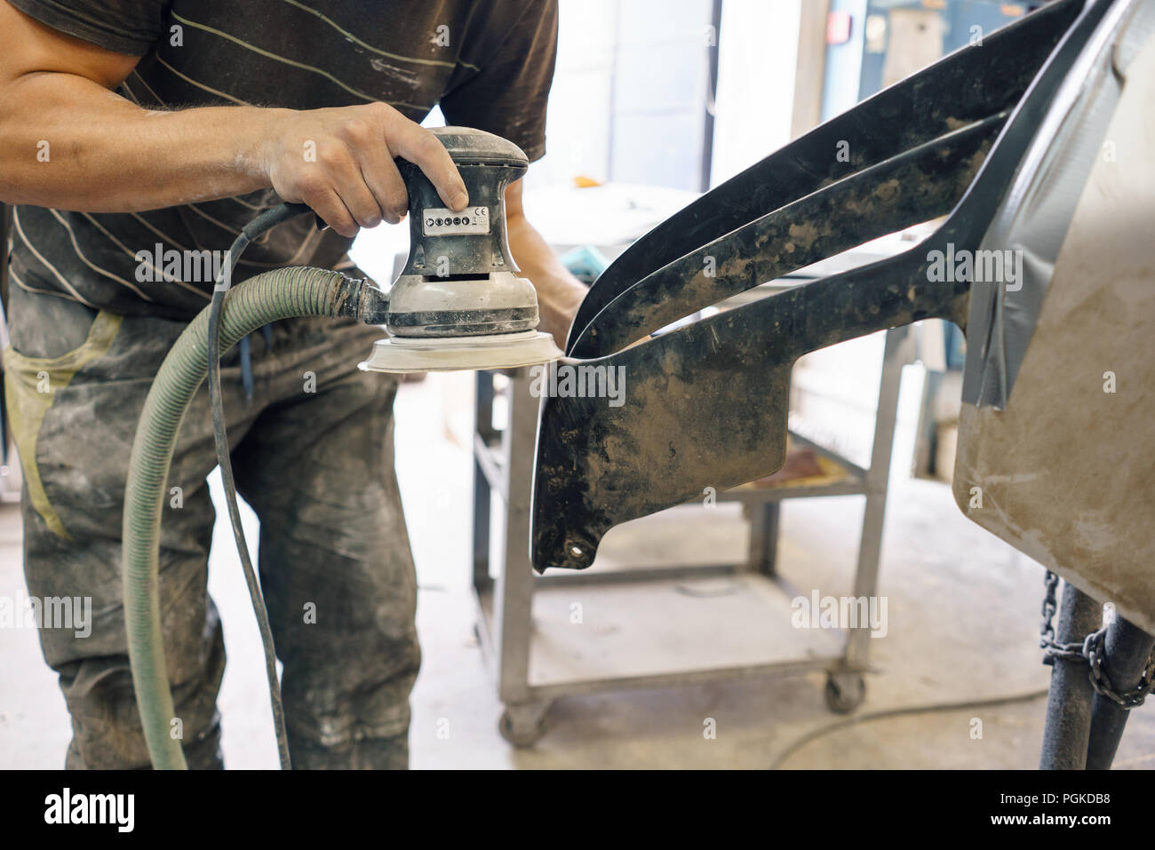 The mechanic works with a grinding machine. Garage painting car service