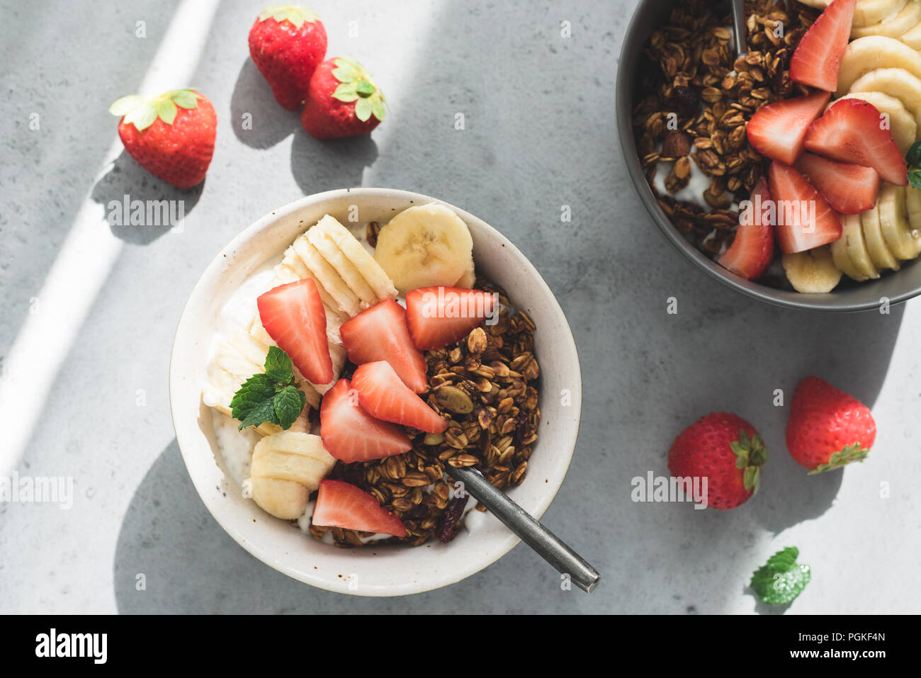 Chia pudding topped with granola and fruits in bowl on gray concrete