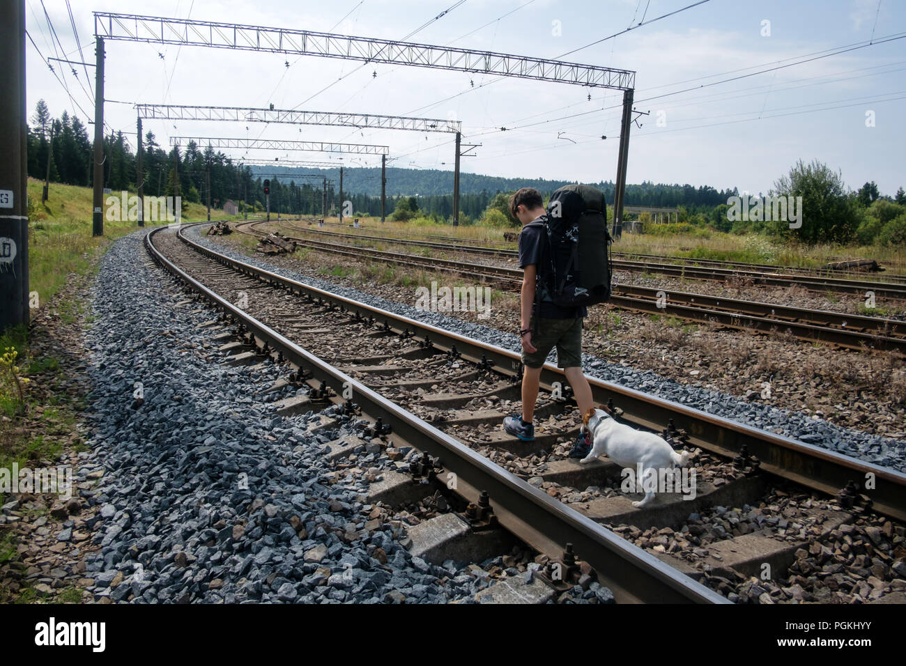 Teenager on railway walking with small white dog Stock Photo