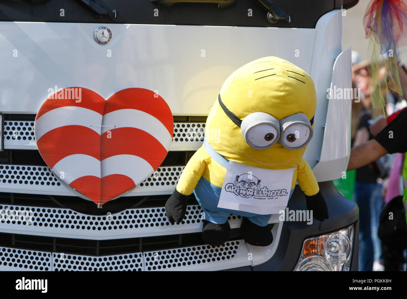 Worms, Germany. 26th Aug, 2018. A red and white striped heart, the symbol of the Backfischfest, and a Minion figure hangs on a float. The first highlight of the 2018 Backfischfest was the big parade through the city of Worms with over 70 groups and floats. Community groups, music groups and businesses from Worms and further afield took part. Credit: Michael Debets/Pacific Press/Alamy Live News Stock Photo