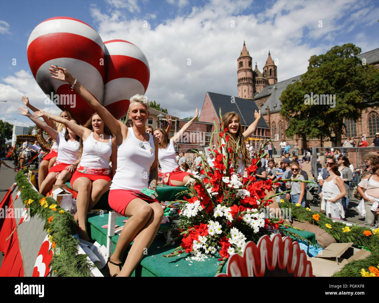Worms, Germany. 26th Aug, 2018. Girls of the Wormser Carneval Club WCC 1974 are pictured on a float in front of a giant red-white striped heart (emblem of the Backfischfest). The first highlight of the 2018 Backfischfest was the big parade through the city of Worms with over 70 groups and floats. Community groups, music groups and businesses from Worms and further afield took part. Credit: Michael Debets/Pacific Press/Alamy Live News Stock Photo