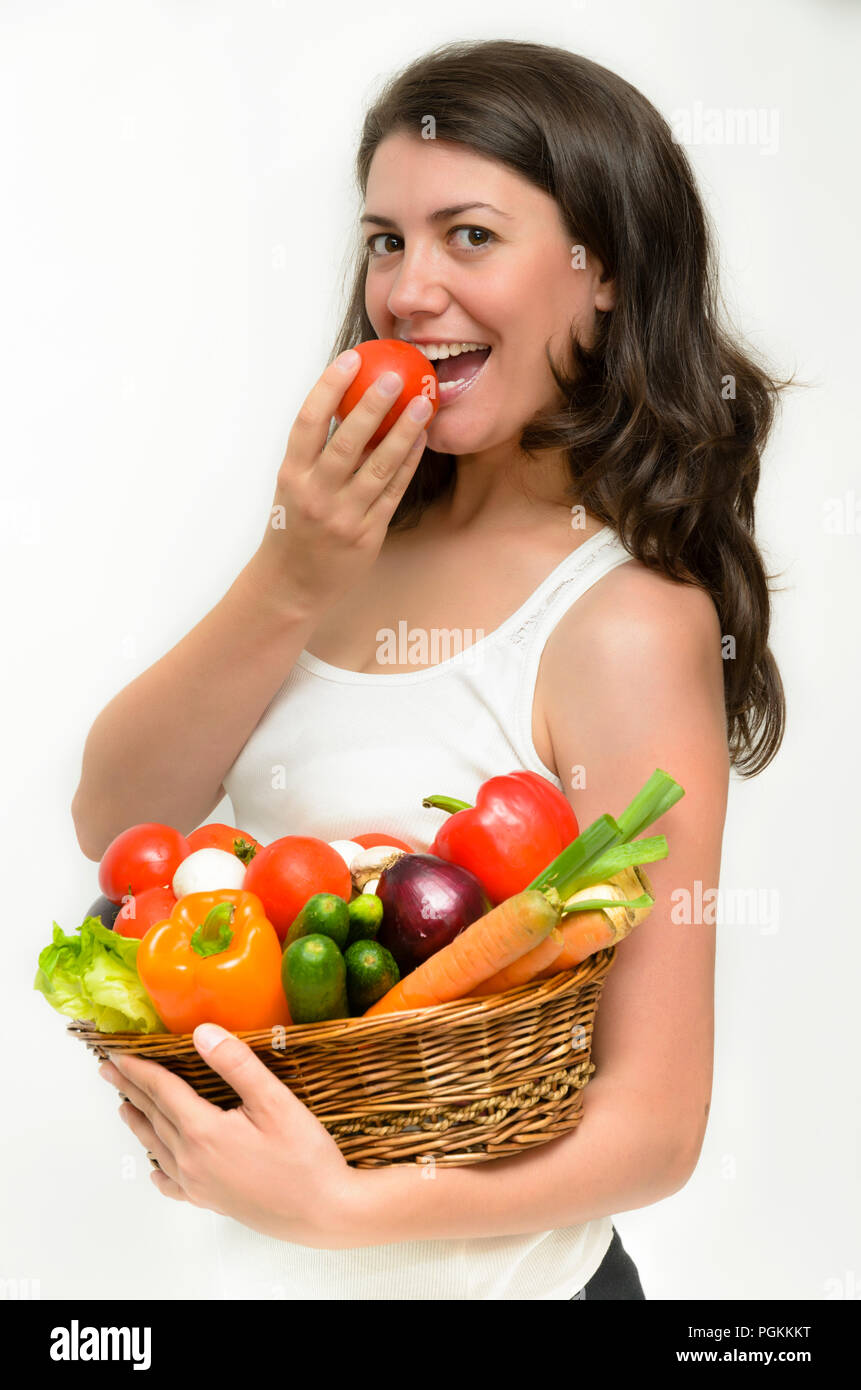 Beautiful young woman holding a basket full of vegetables Stock Photo