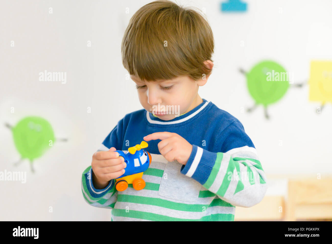 Cute serious boy examining a toy at kindergarten Stock Photo