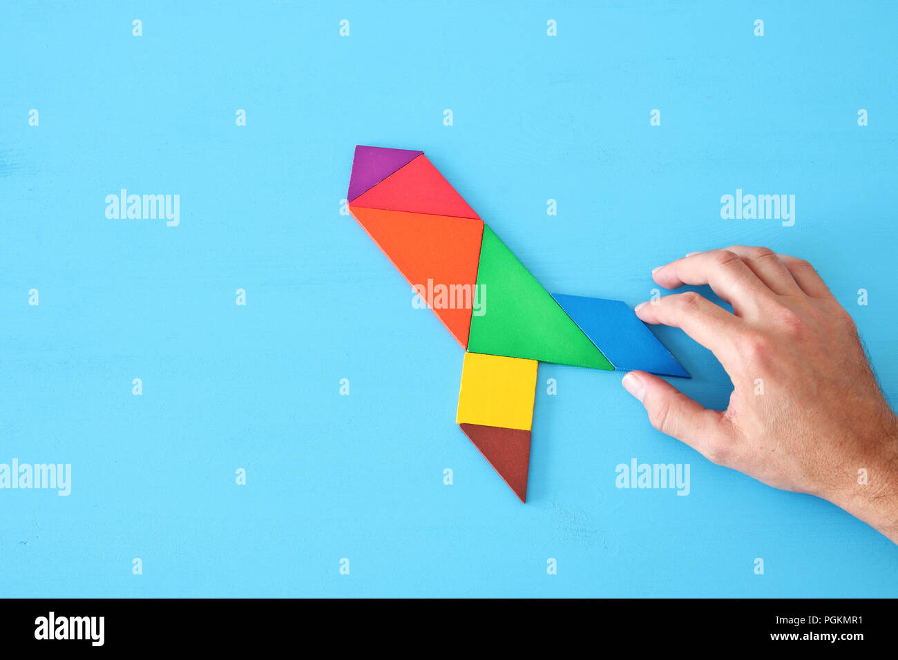 rocket made from tangram puzzle on blue pastel wooden background Stock ...
