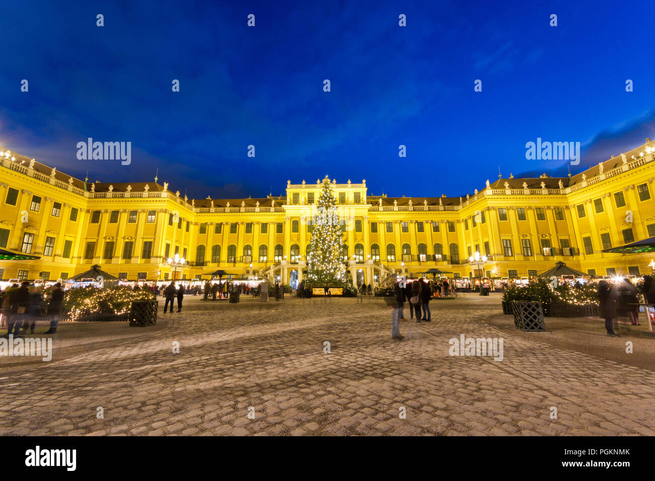 Schönbrunn Christkindlmarkt christmas market with illuminated palace and fairy lights decorated Christmas tree at dusk in Advent. Stock Photo