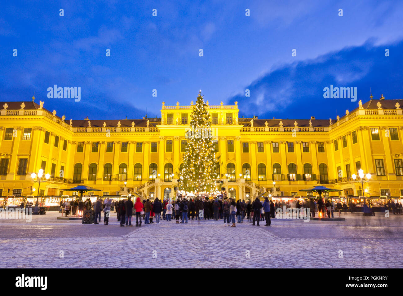 Schönbrunn Christkindlmarkt christmas market with illuminated palace and fairy lights decorated Christmas tree at dusk in Advent. Stock Photo