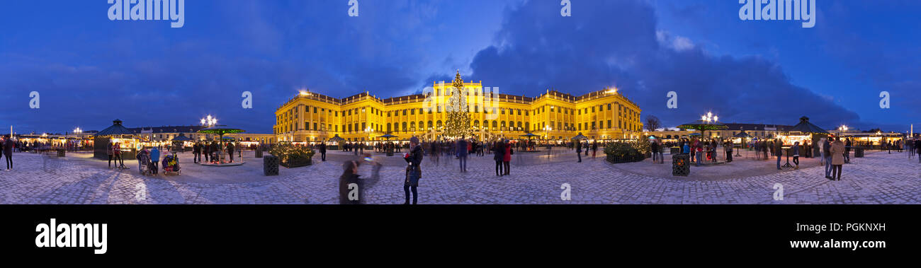 Schönbrunn Christkindlmarkt christmas fair panorama with illuminated palace and fairy lights decorated Christmas tree at dusk in Advent. Stock Photo