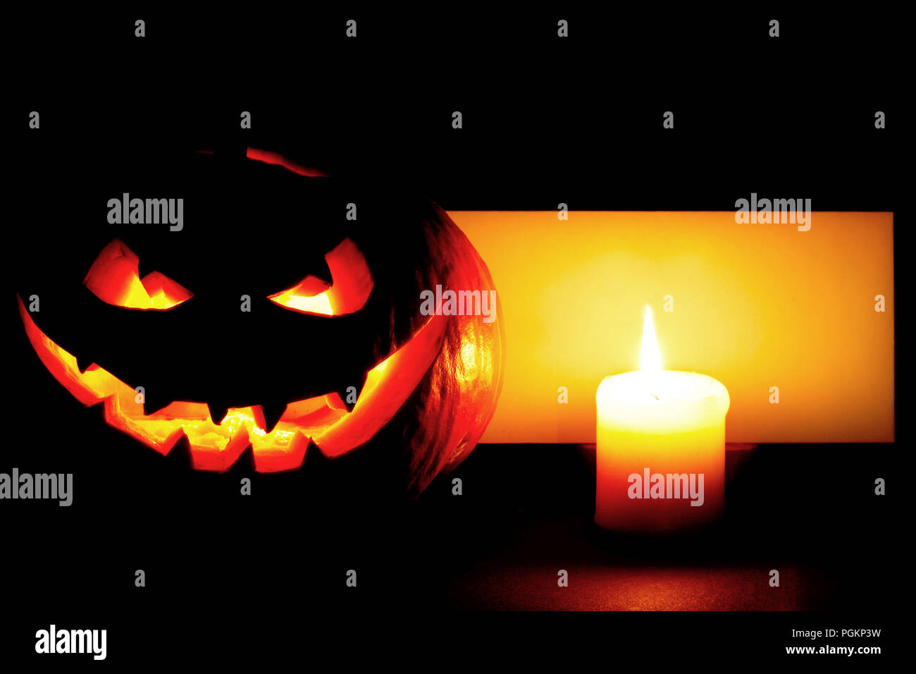 Halloween pumpkin with blank post card and candle on black background Stock Photo