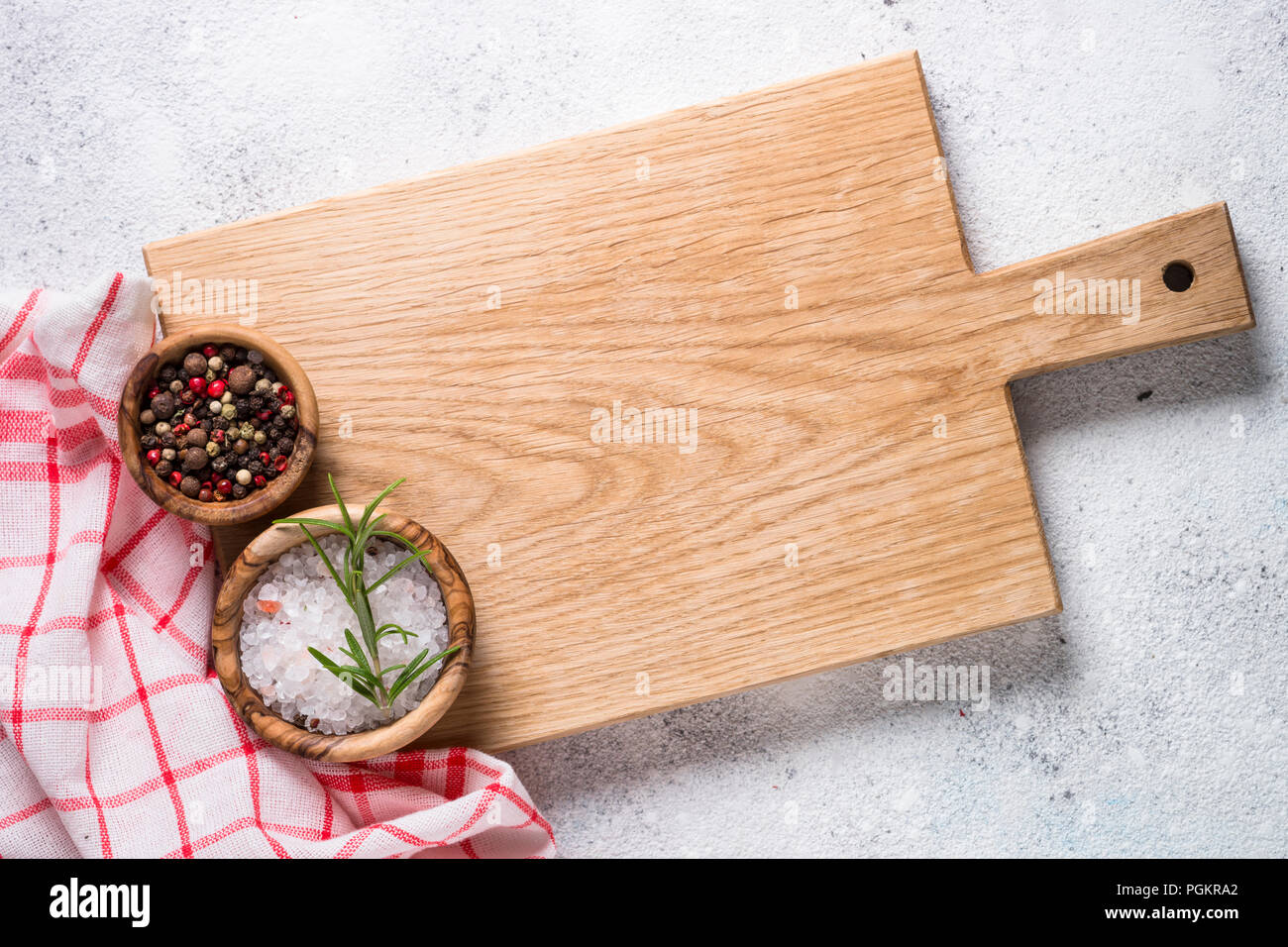 Empty wooden cutting board and tablecloth on white stone table. Stock Photo