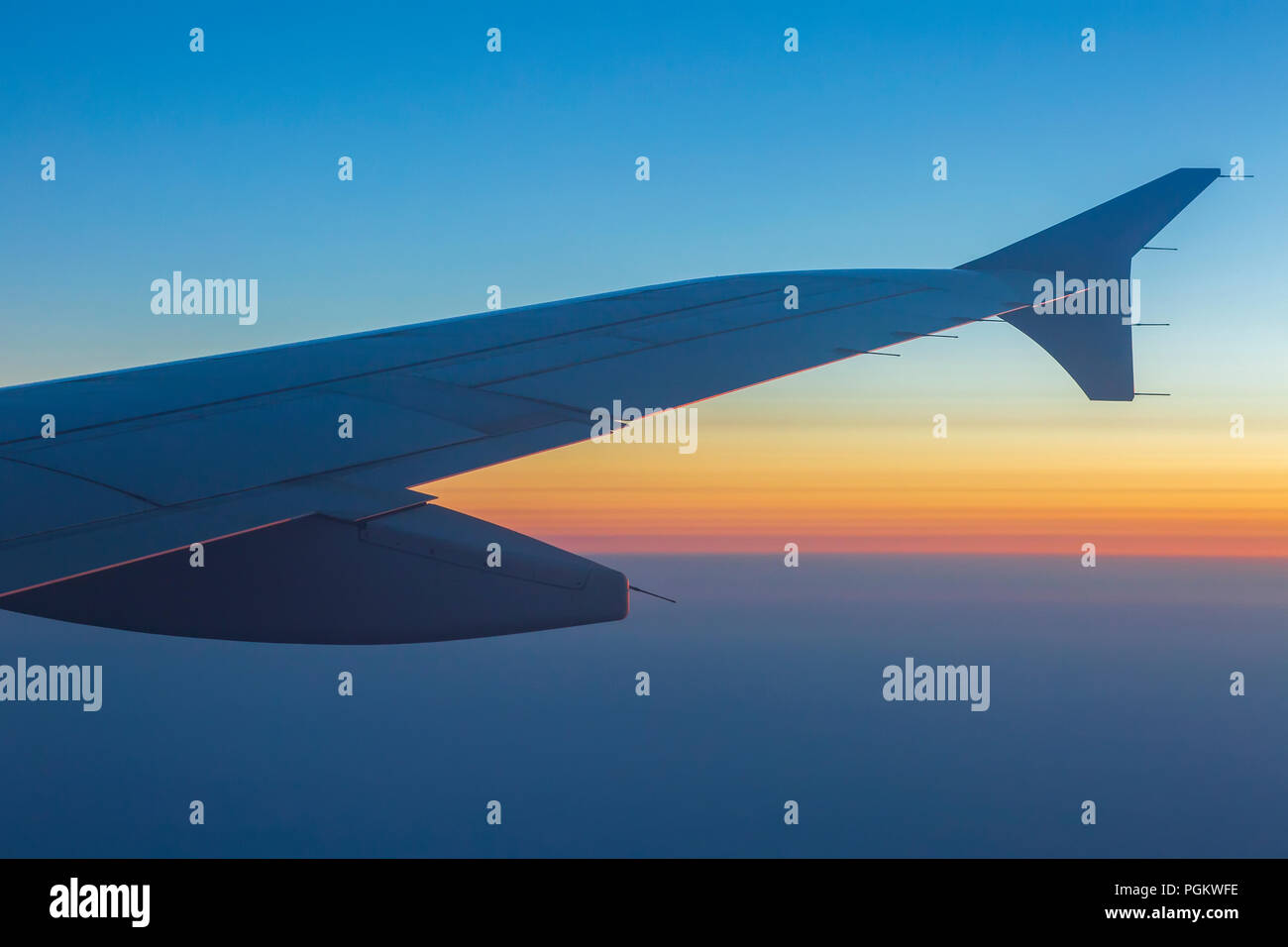 Wing of an airplane in the sunset. Airplane wing out of window. Stock Photo