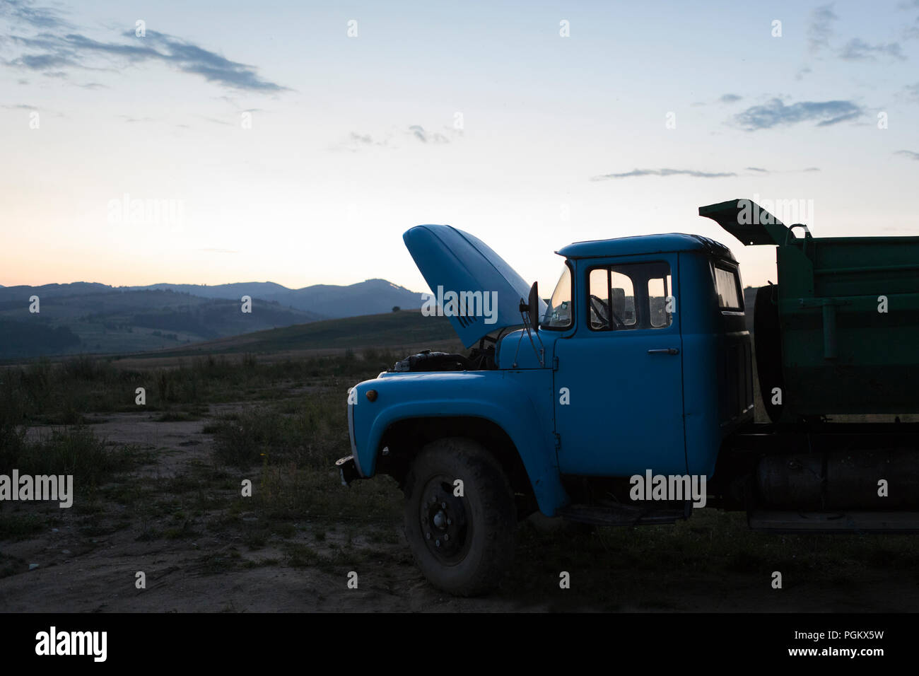 Truck with open motor hood while is setting behind mountains landscape in Bulgaria Stock Photo