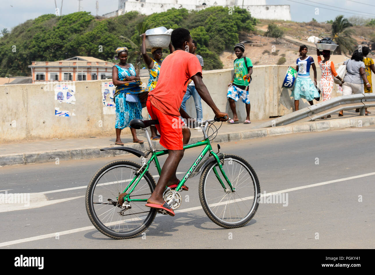 ELMINA, GHANA -JAN 18, 2017: Unidentified  Ghanaian boy rides a bicycle on the road in Elmina. People of Ghana suffer of poverty due to the bad econom Stock Photo