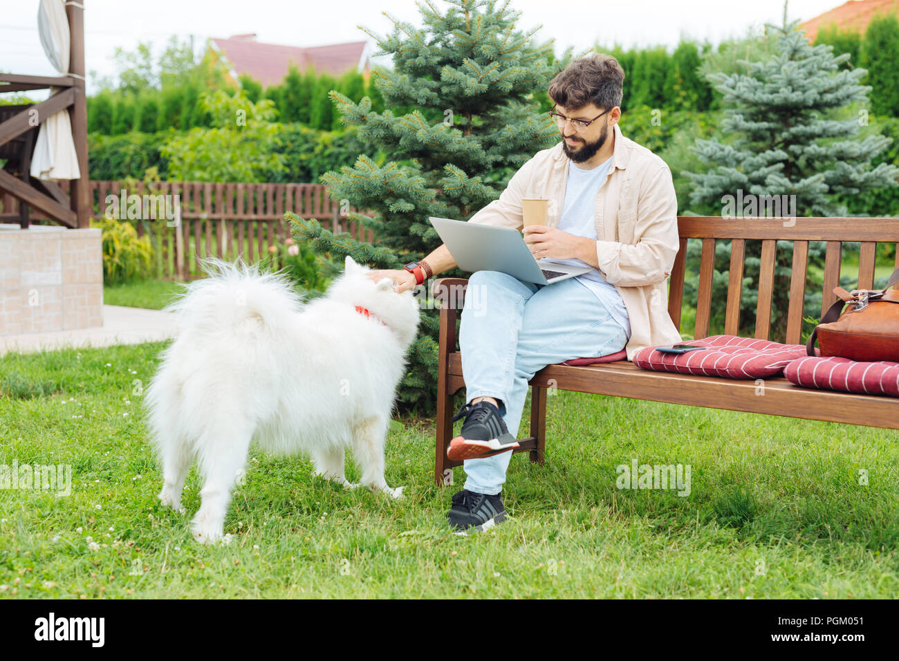 Bearded man sitting on the bench while working in home territory Stock Photo