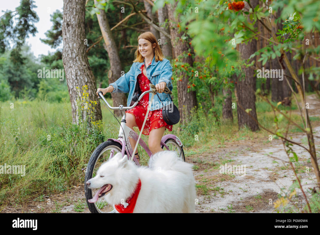 Fashionable happy woman riding bike on warm summer day Stock Photo