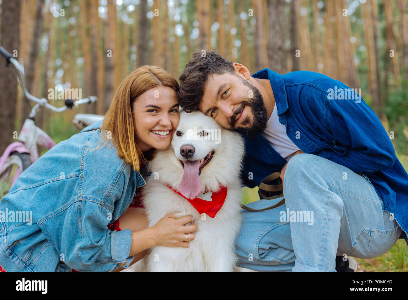 Stylish couple wearing denim clothes leaning on their white dog Stock ...