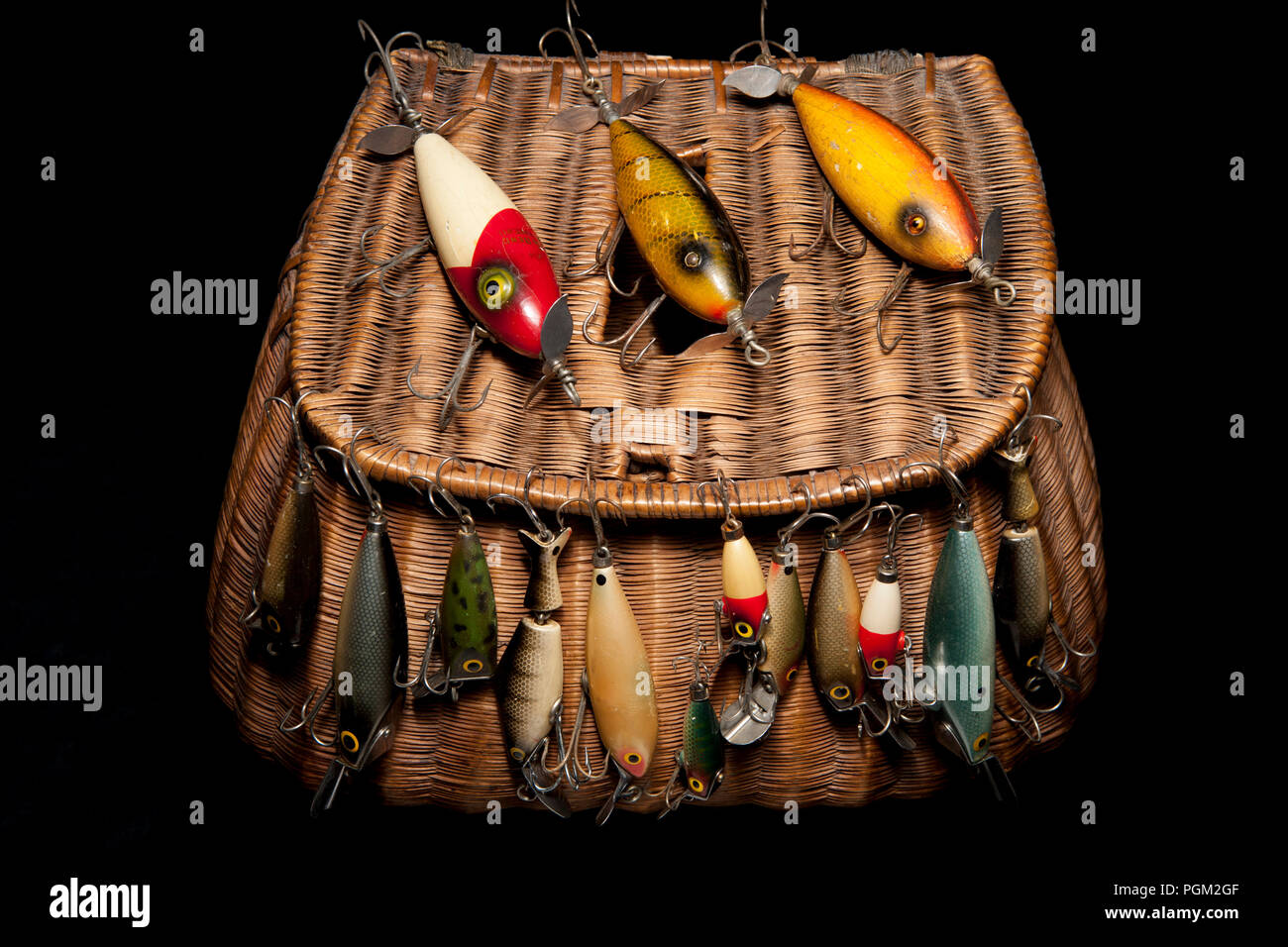 A selection of old fishing lures, or plugs, displayed on an old whicker fishing creel. From a collection of fishing tackle and sporting collectibles.  Stock Photo
