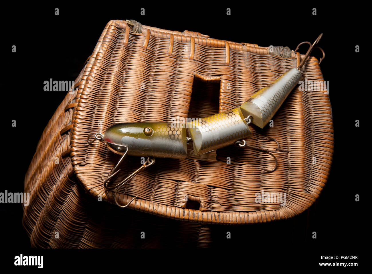 A large, jointed fishing lure, or plug, equipped with treble hooks and displayed on an old whicker fishing creel. From a collection of fishing tackle  Stock Photo