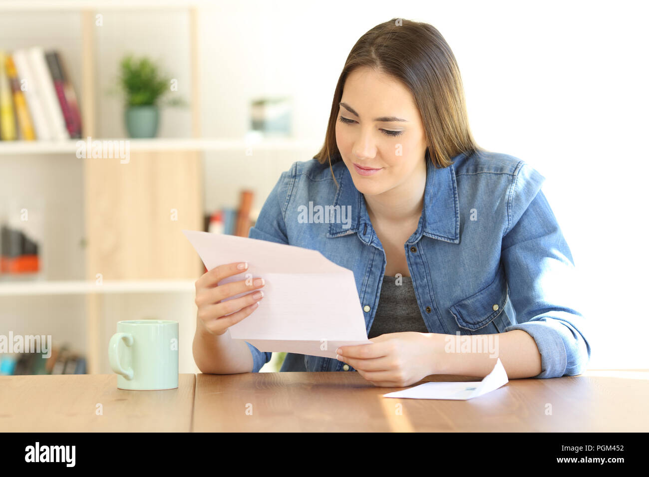 Relaxed lady reading a letter on a table at home Stock Photo