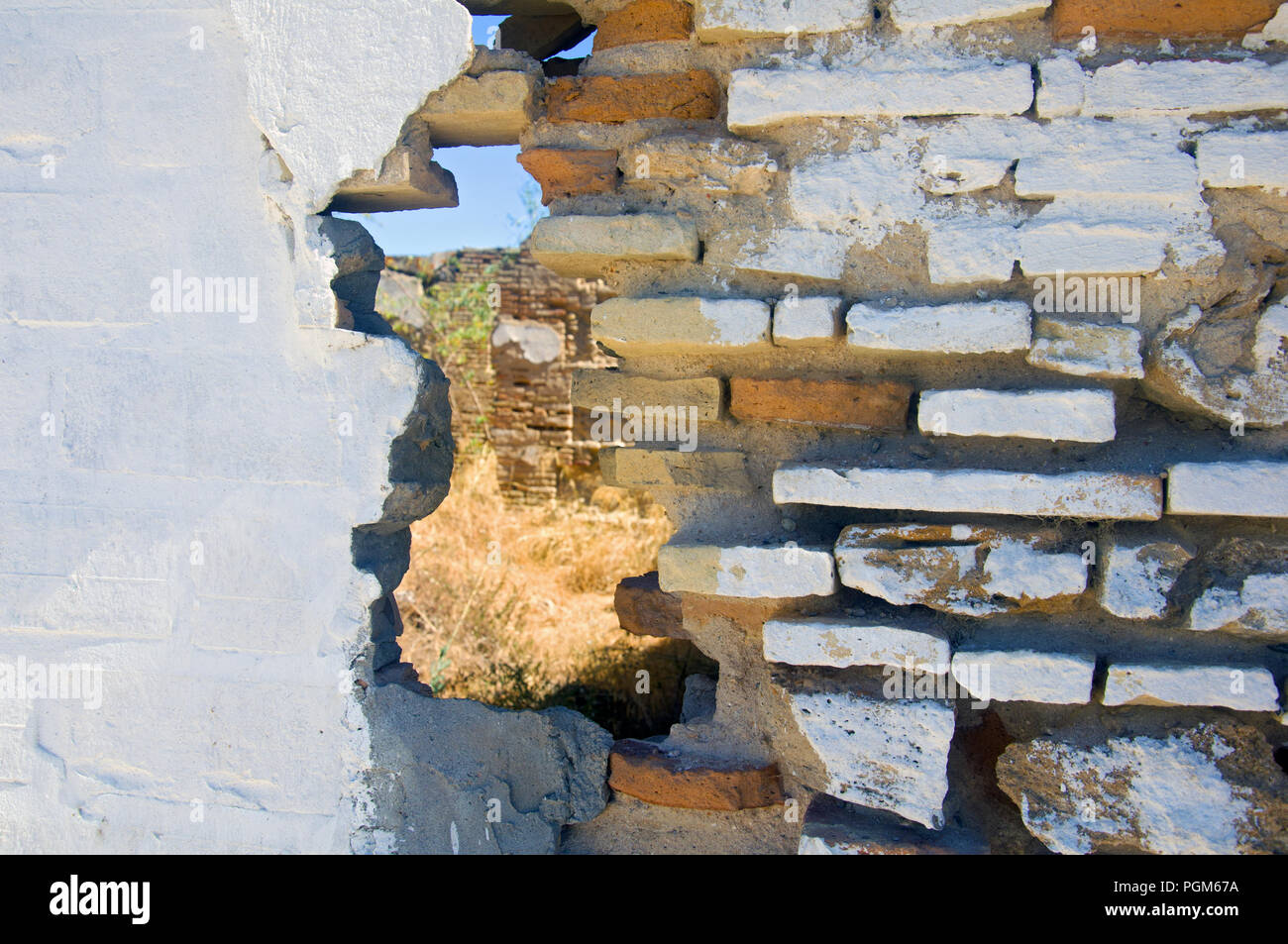 Hole in the different structured wall, dry grass Stock Photo