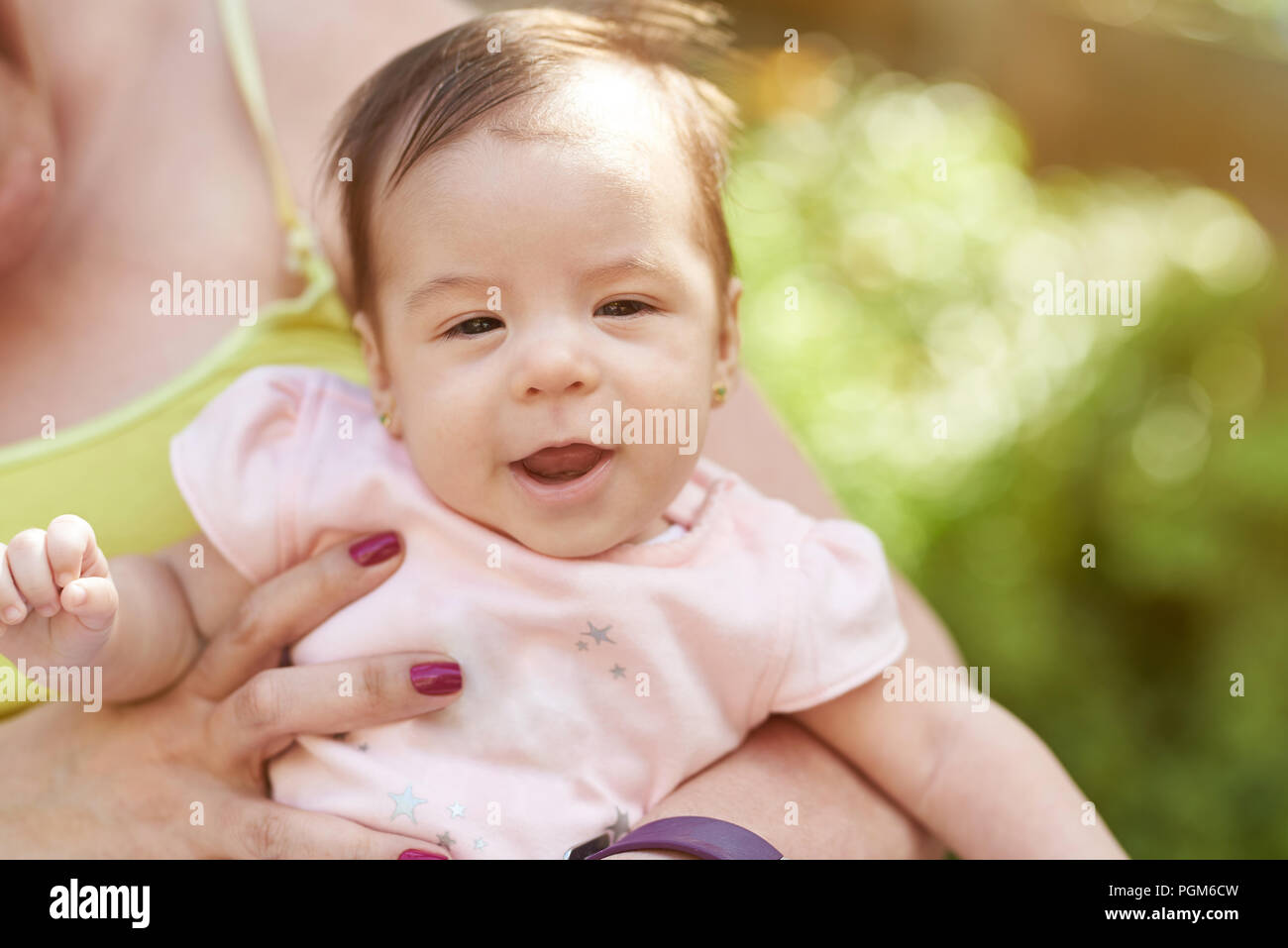 Happy baby in mom hands close up portrait on sunny background Stock Photo