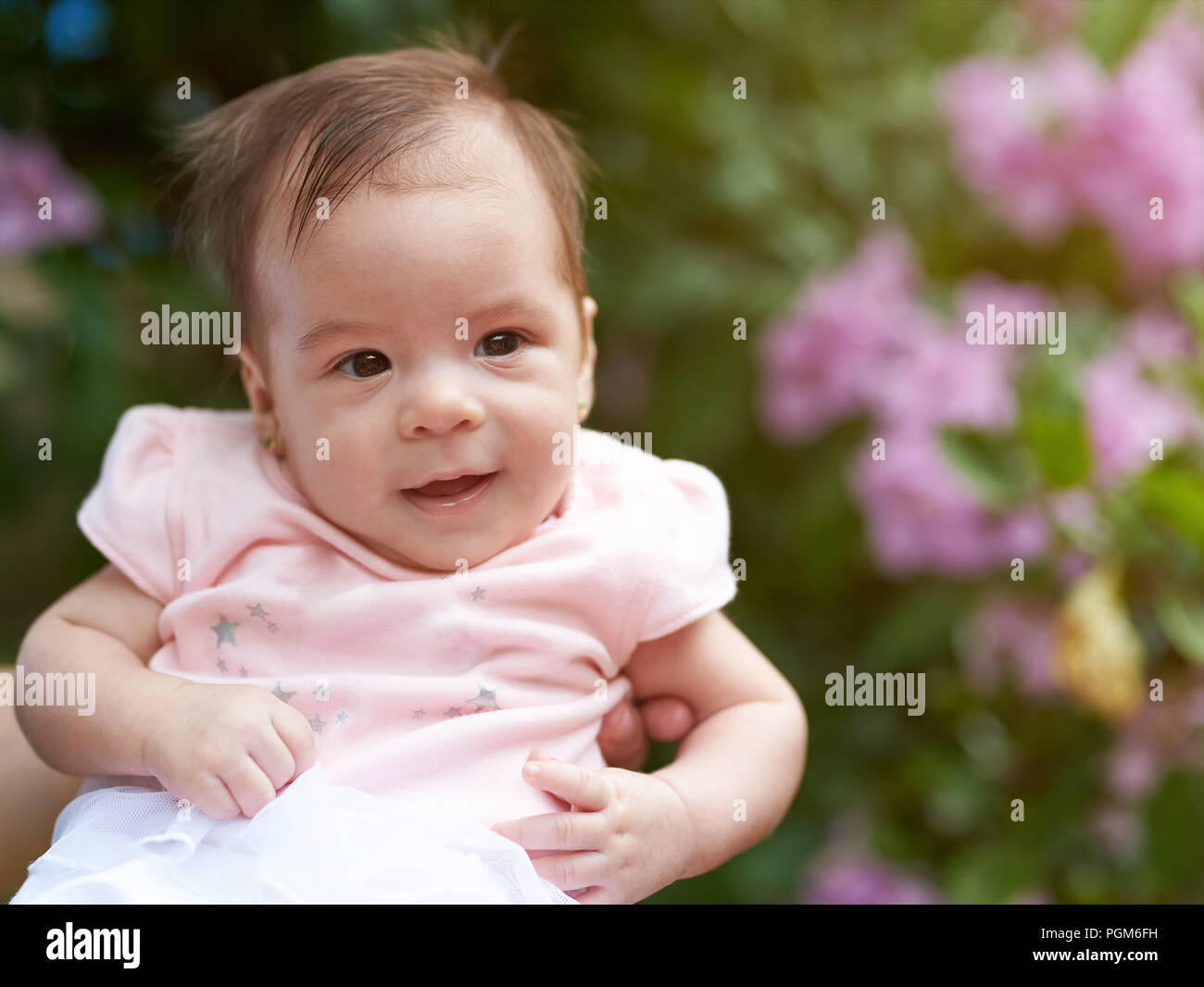 Portrait of smiled baby girl on blurred green background Stock Photo