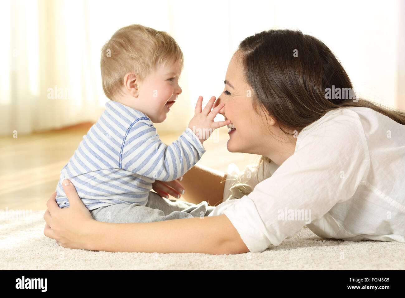 Affectionate mother and baby playing together on a carpet on the floor at home Stock Photo