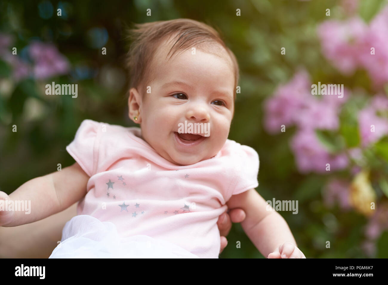 Smiling newborn baby on blurred green summer background Stock Photo