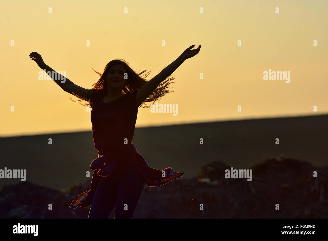 Teen girl jump against beautiful sunset on field Stock Photo