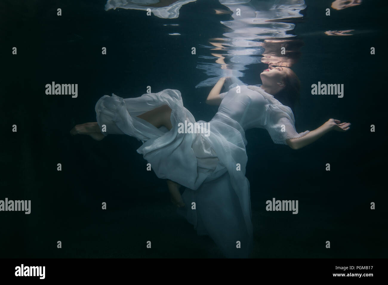 Beautiful woman in a white dress swims under the water Stock Photo - Alamy