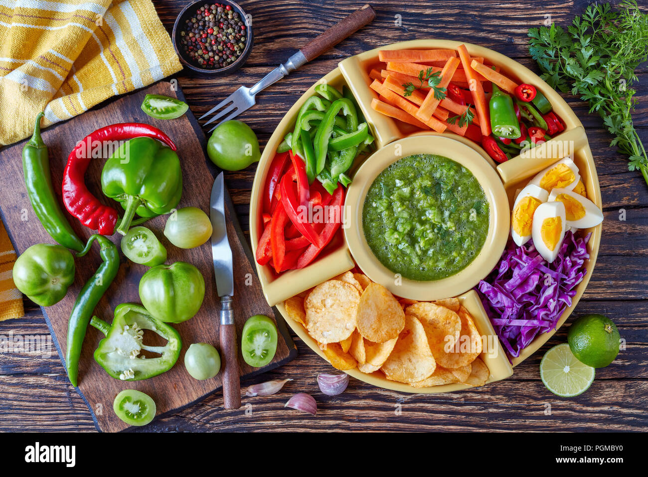 green salsa verde and mexican set for tacos consist of chopped fresh vegetables, hard boiled eggs and chips in bowls on old rustic wooden table with i Stock Photo
