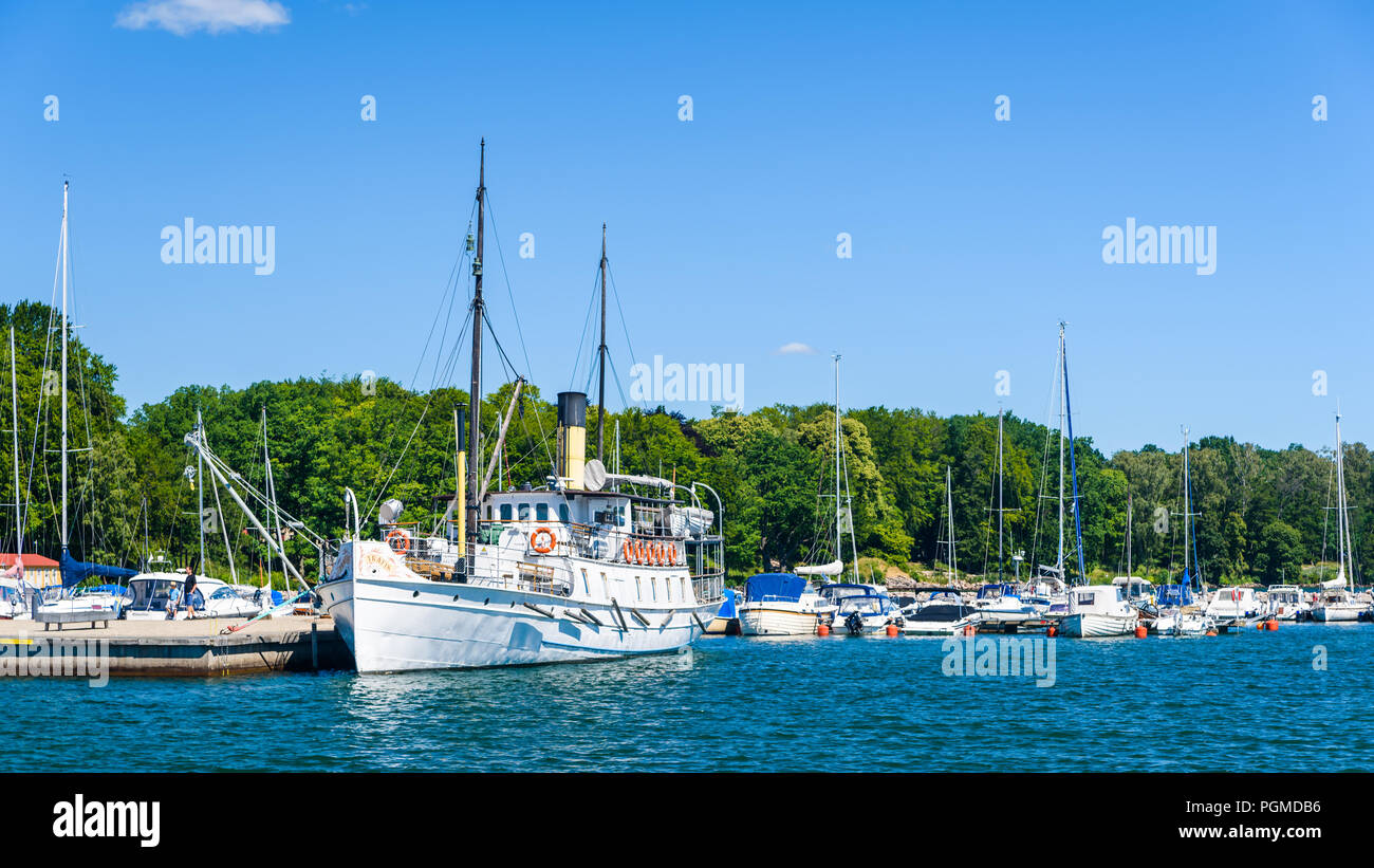 Hjo, Sweden – July 2, 2018: The marina seen from the lake with the historical passenger steamboat S/S Trafik from 1892, moored by a pier on an ordinar Stock Photo