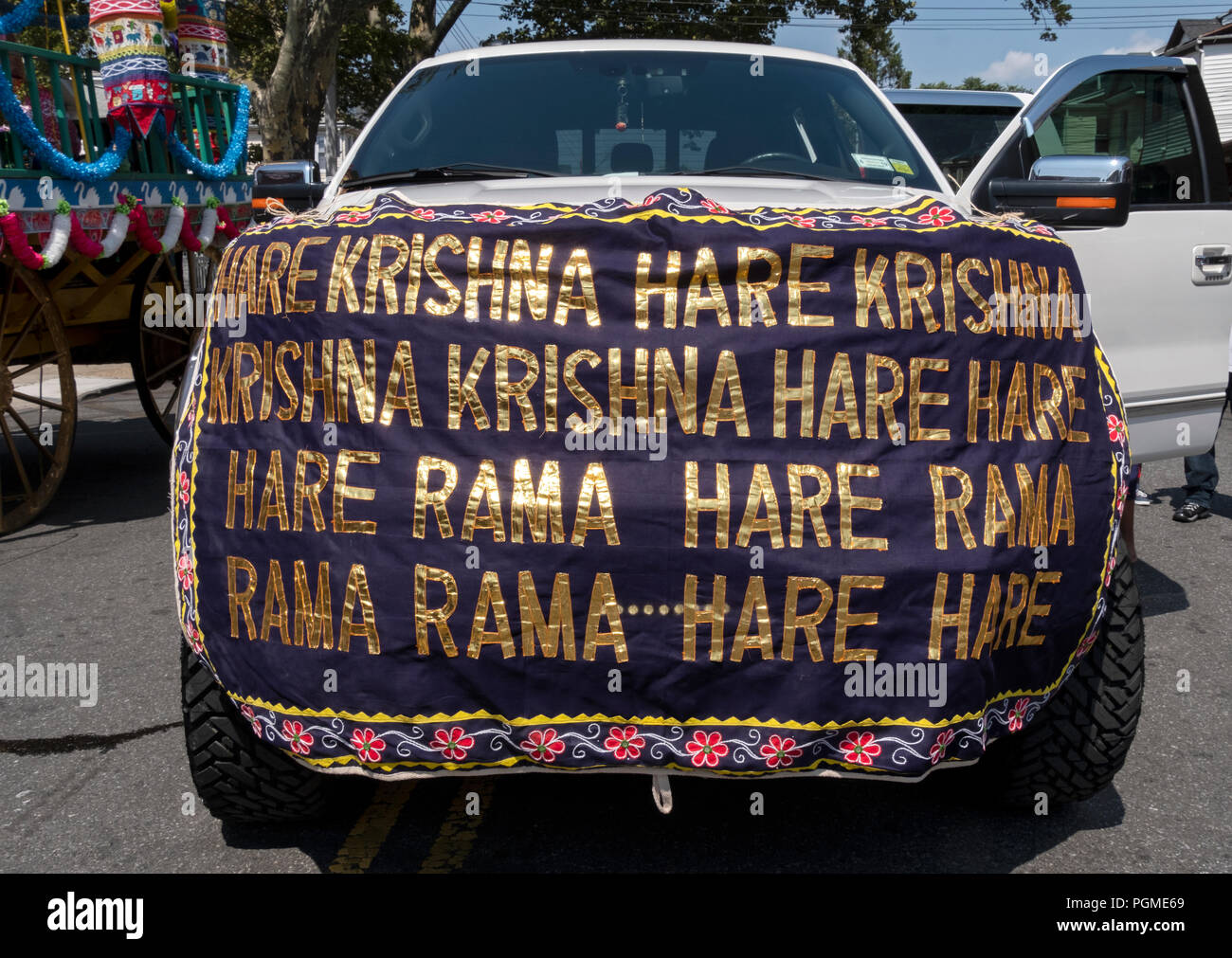 An SUV at the Queens, New York Rathayatra Parade with the 16 word Hare Krishna mantra on a banner. Stock Photo
