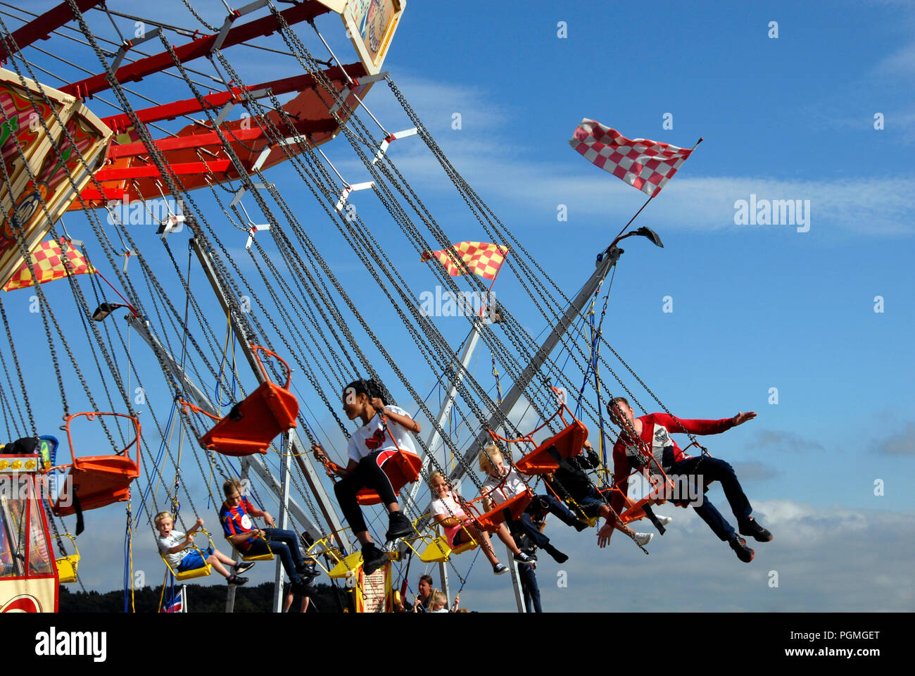 Young people riding on roundabout at fairground Stock Photo