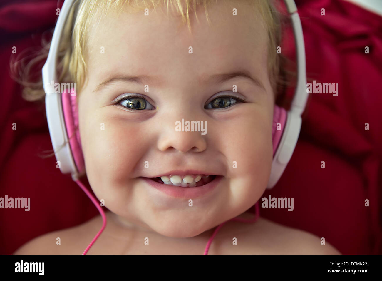 Beautiful baby in baby carriage playing with earphones unplugged Stock Photo