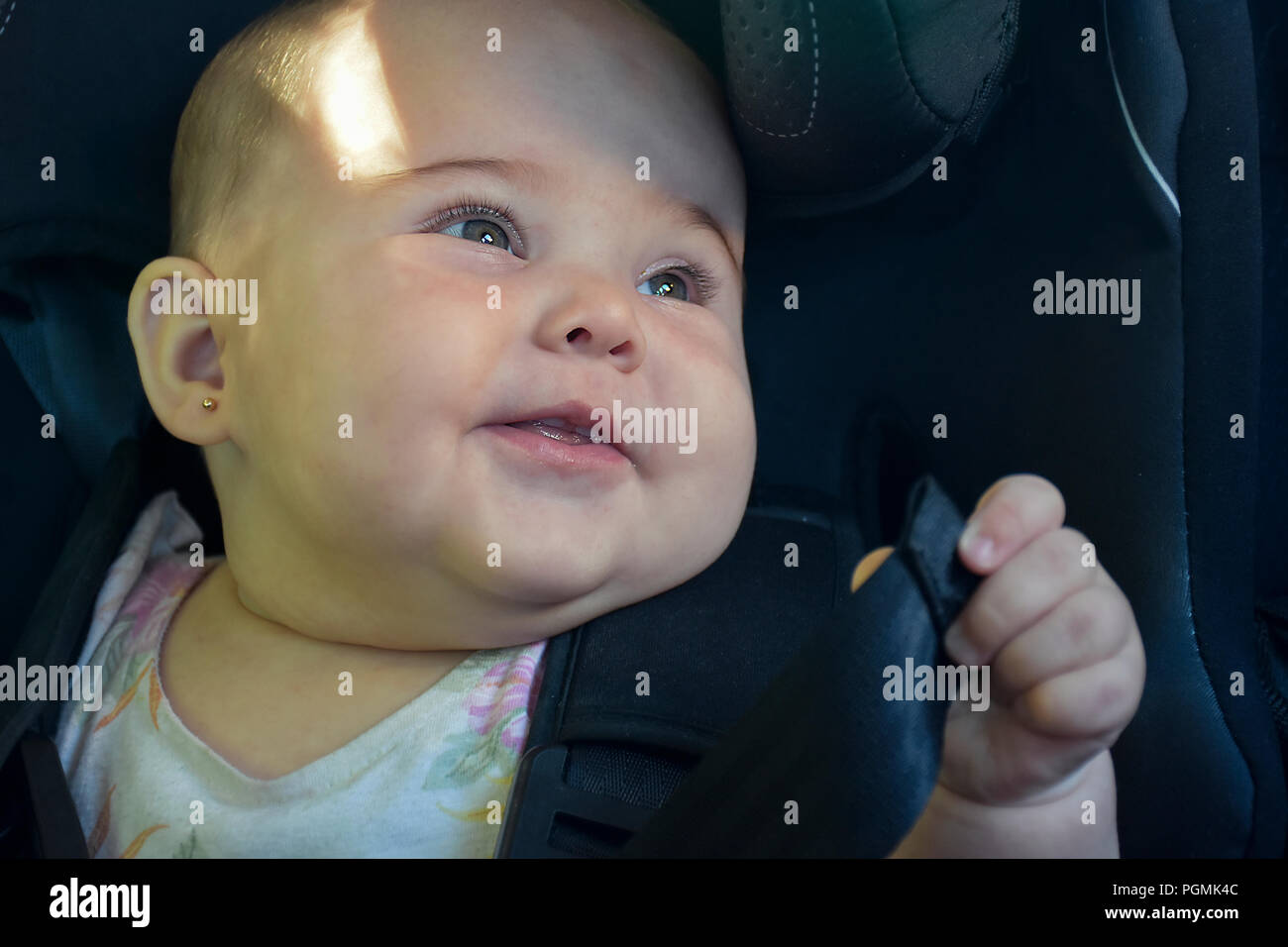 Beautiful baby in baby seat in the car having a pleasant trip Stock