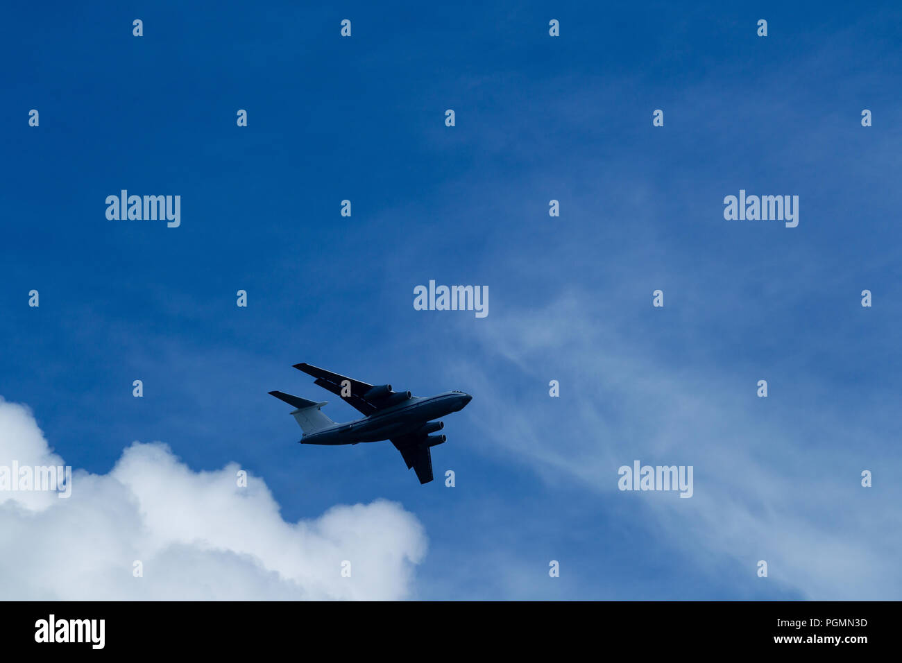 Transport plane flies against the background of a summer blue sky with ...
