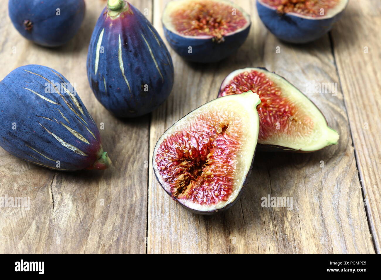 Fresh dark purple figs cut in halves on wooden surface Stock Photo