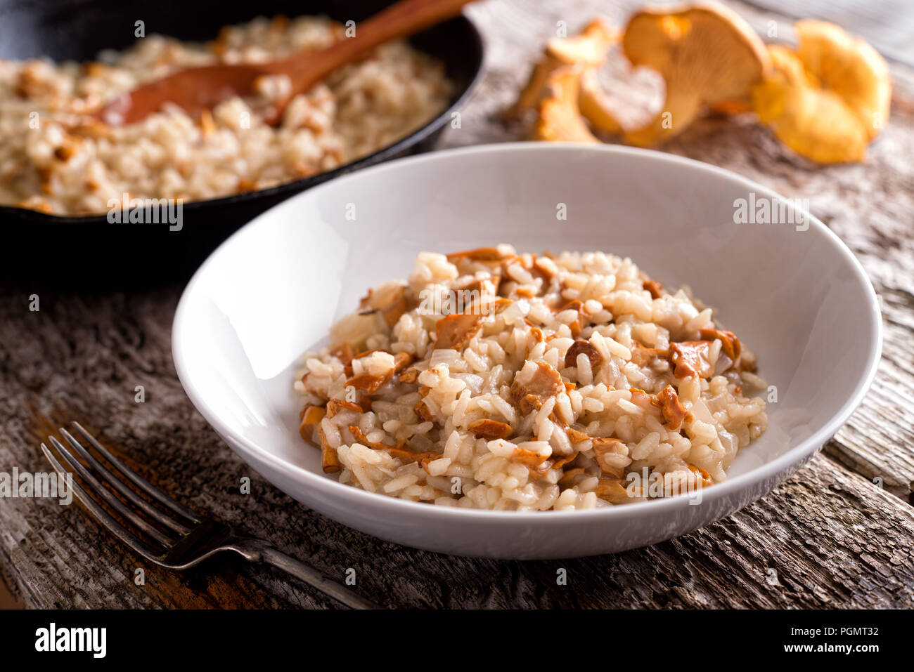 A bowl of delicious chanterelle risotto on a rustic wood table top. Stock Photo
