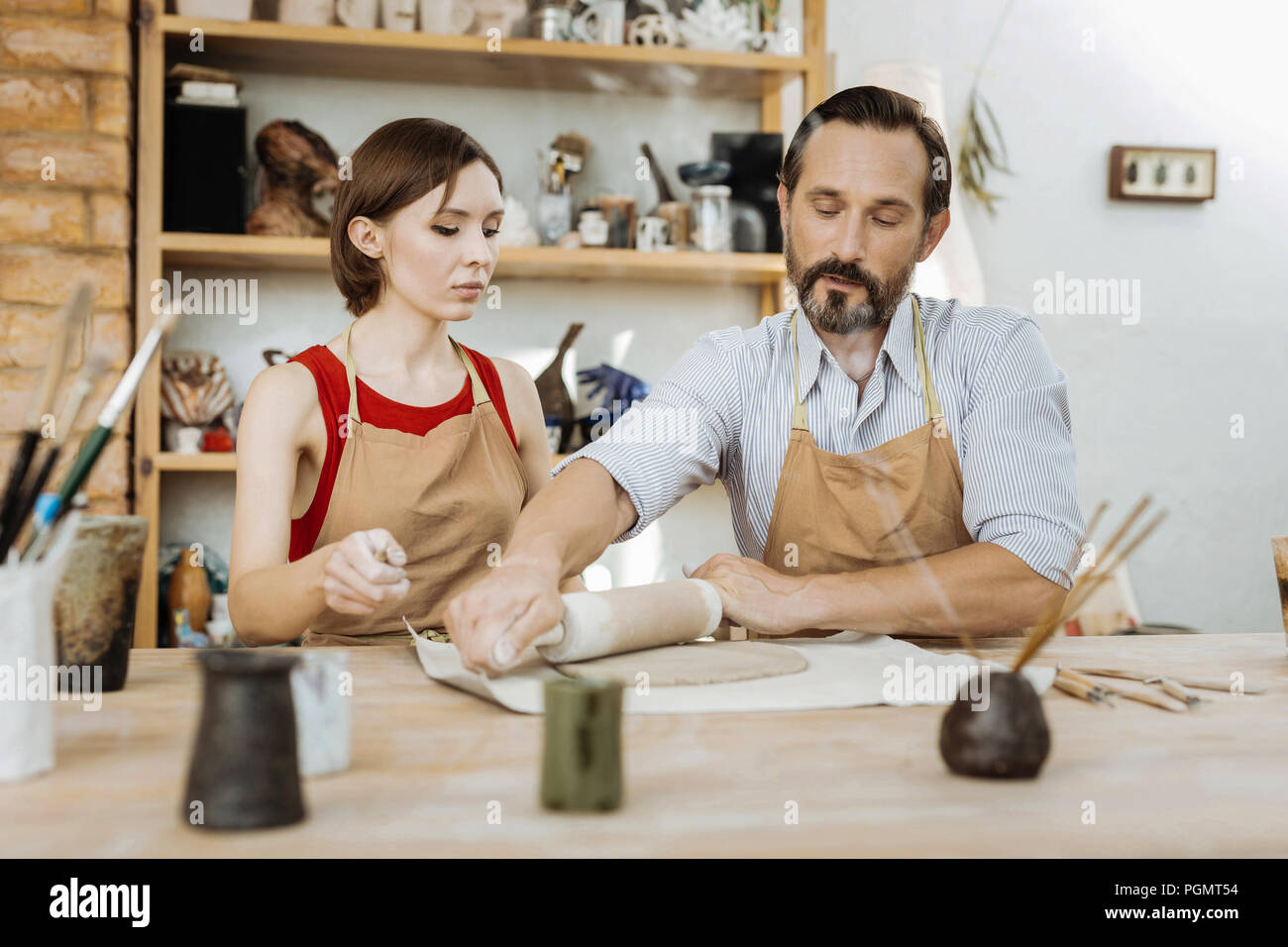 Bearded dark-haired handicraftsman giving master class for woman Stock Photo