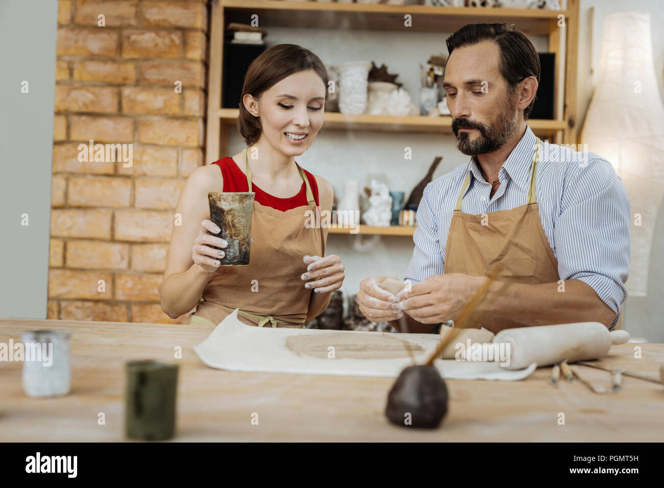 Smiling dark-haired housewife visiting master class in pottery Stock Photo