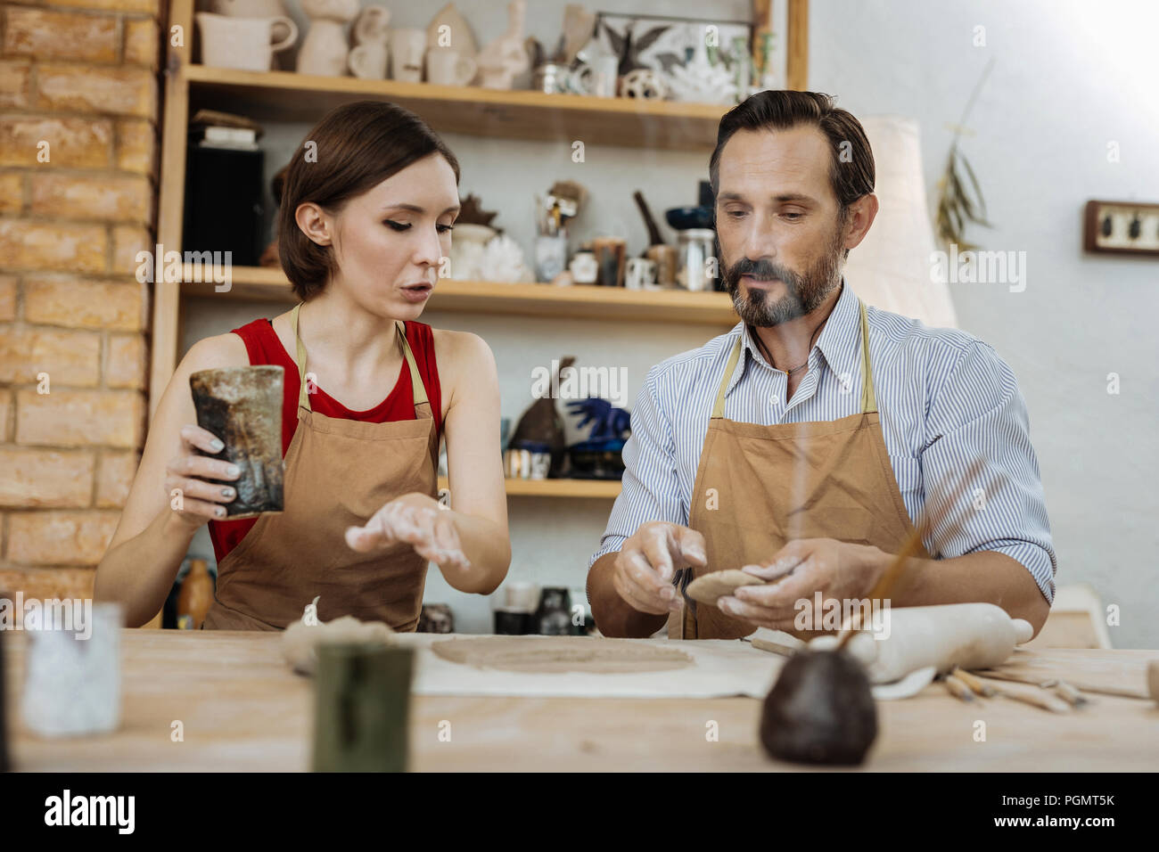 Dark-haired woman asking questions during ceramics master class Stock Photo
